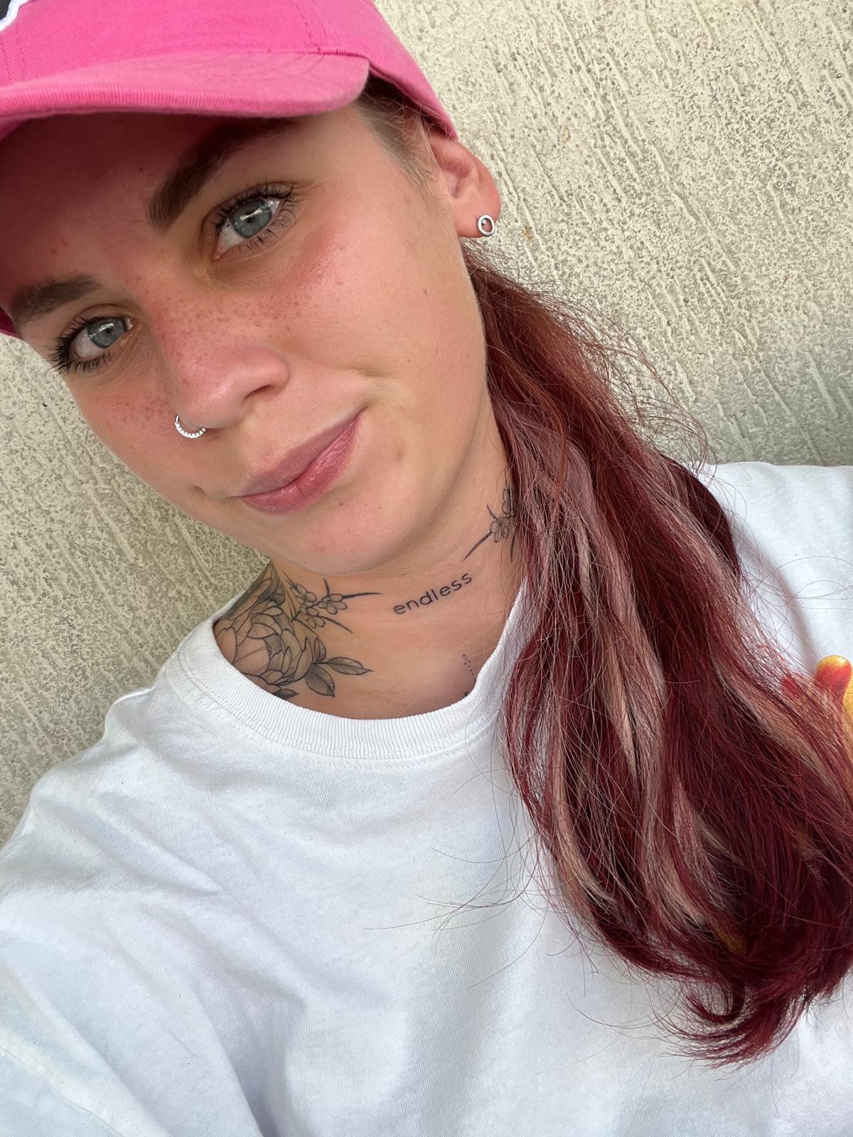 Natürliches Porträt einer Frau mit pinker Cap und roten Haaren, Nahaufnahme vor neutralem Hintergrund – authentische Portraitfotografie, minimi fotografie.